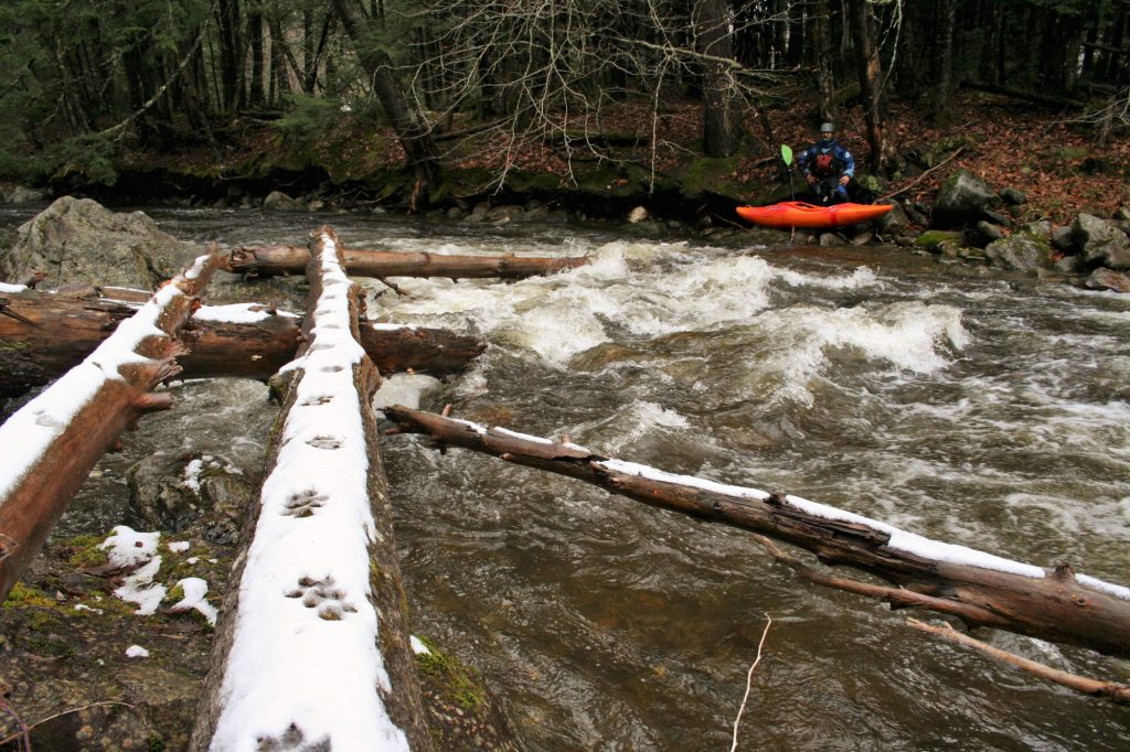 Simone Orlandi portages a log on the Trout River Vermont Whitewater Kayaking