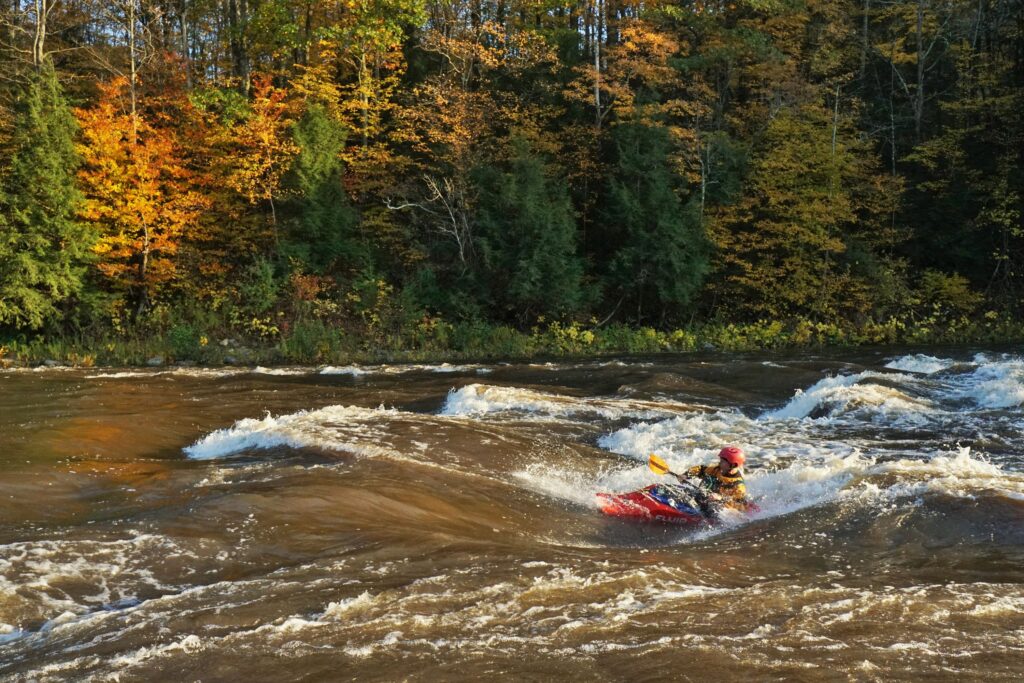 Kayaker Clay Murphy surfs a wave on the 5 Chutes Rapids of the Lamoille River Vermont whitewater kayaking