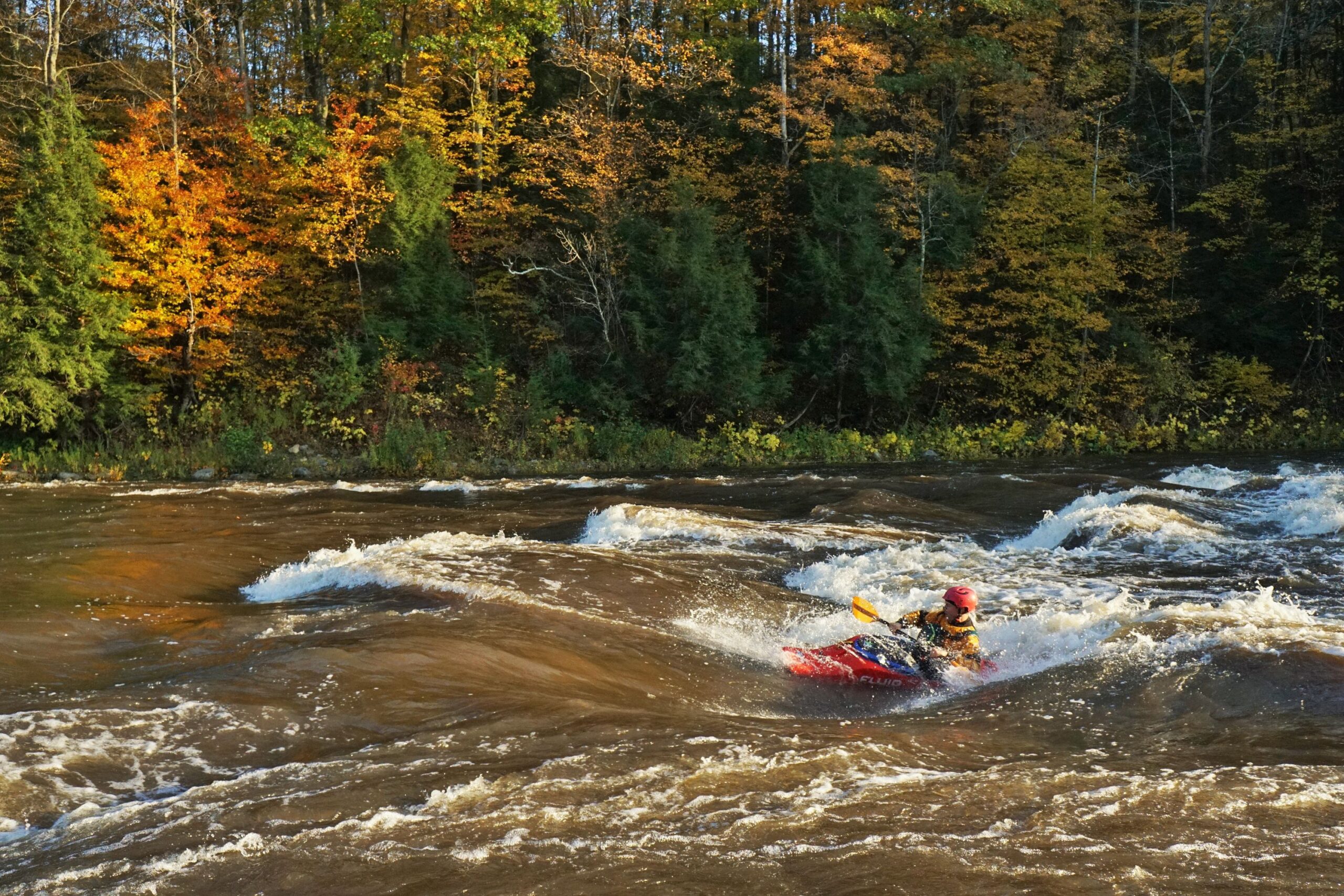 Kayaker Clay Murphy surfs a wave on the 5 Chutes Rapids of the Lamoille River Vermont whitewater kayaking